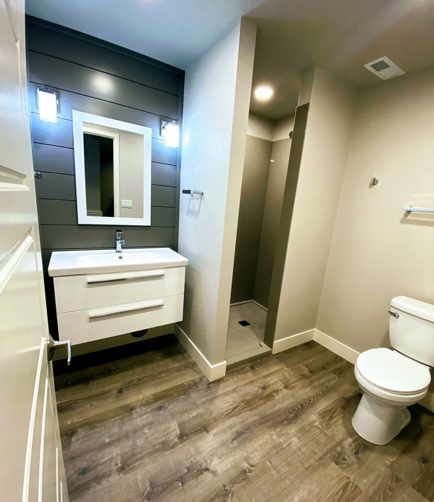 A bathroom with a toilet , sink , mirror and walk in shower.