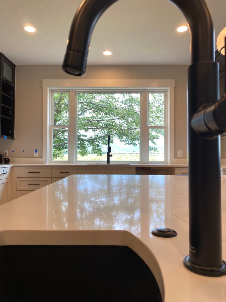 A kitchen with a sink and a window with trees in the background