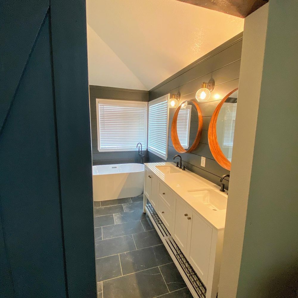 A bathroom with two sinks , a tub and two mirrors.