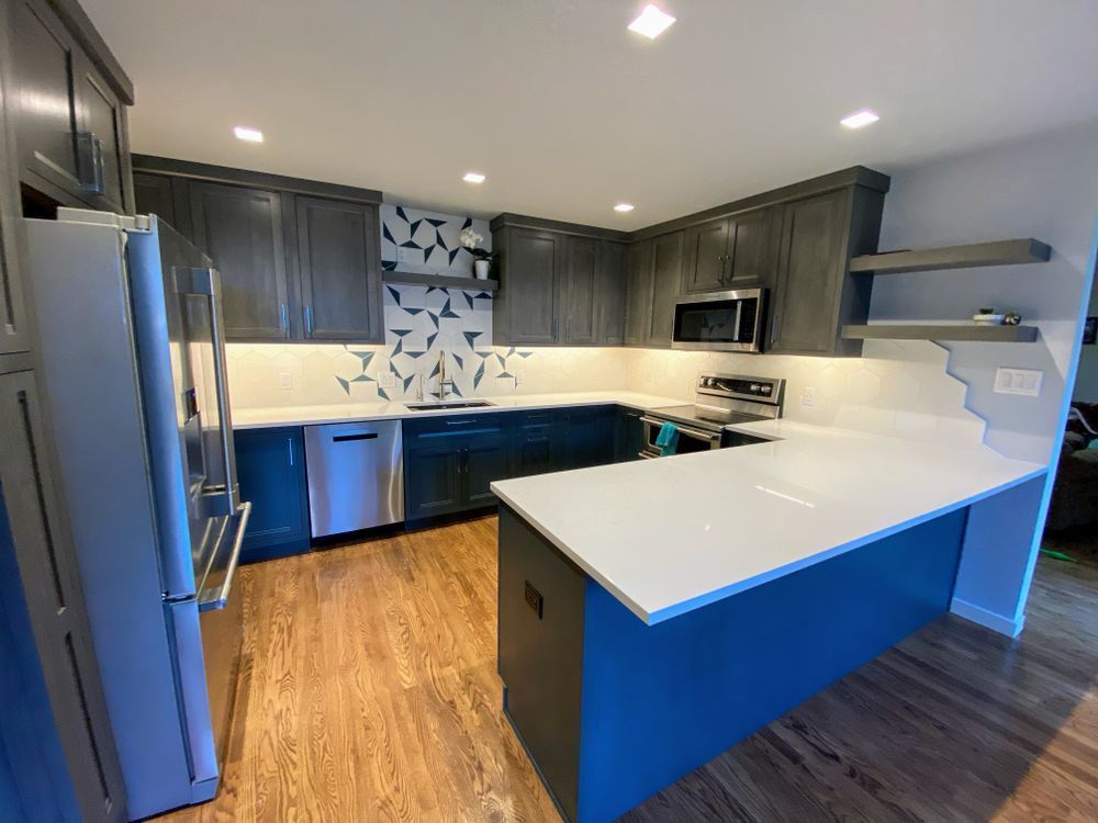 A kitchen with blue cabinets , white counter tops , stainless steel appliances and a large island.