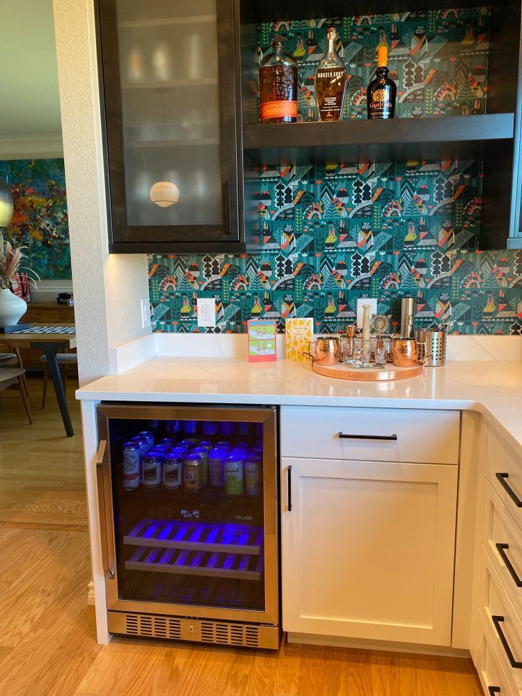 A kitchen with a wine cooler and a bar.