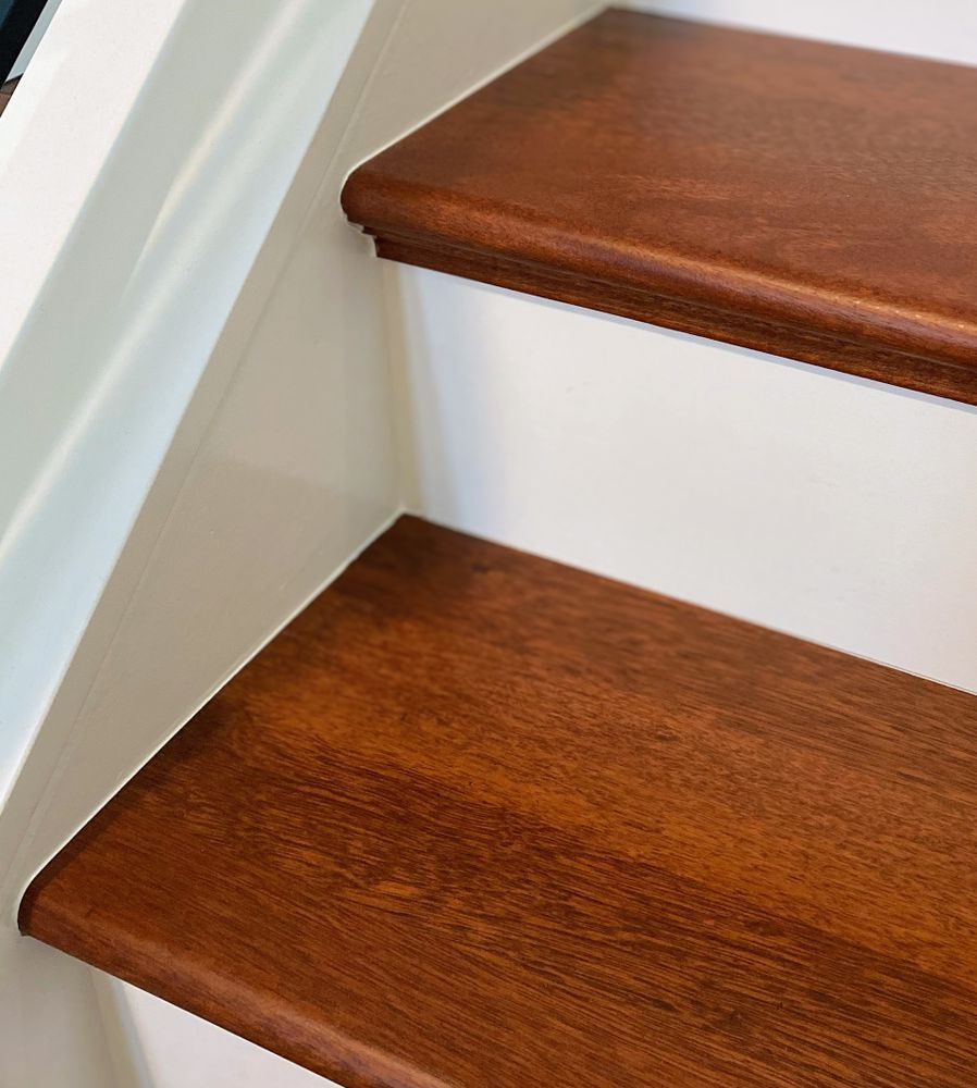 A close up of a wooden staircase with a white railing