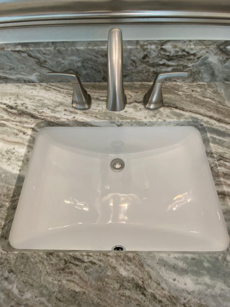 A bathroom sink with a faucet on a granite counter top.