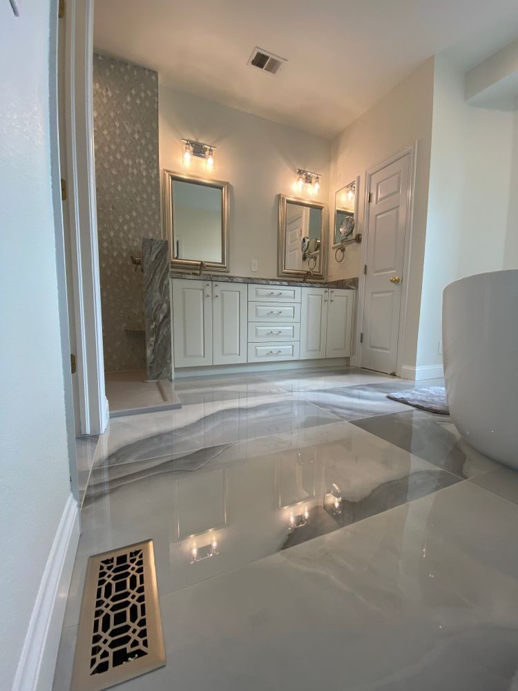 A bathroom with white cabinets , a tub , a mirror and a toilet.