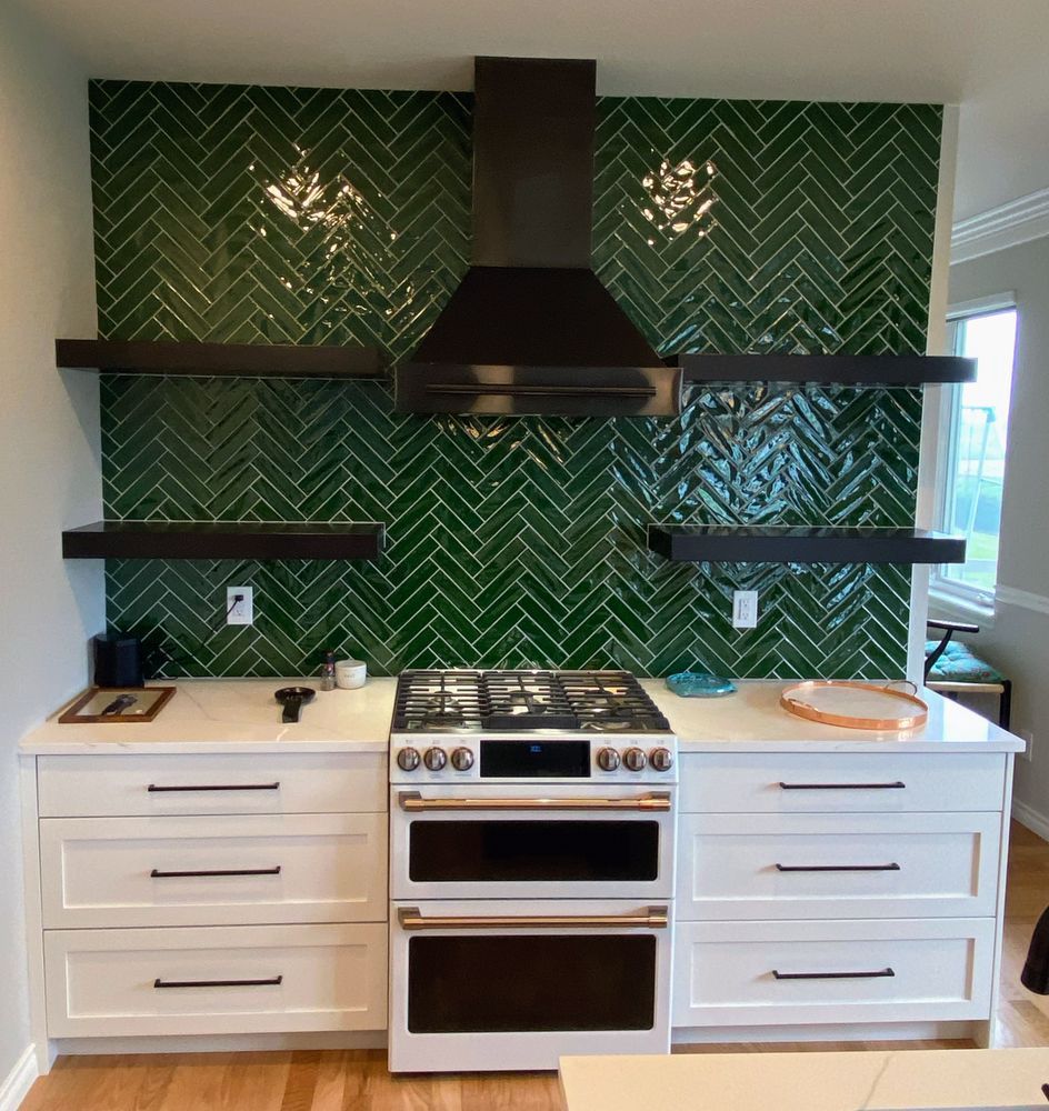 A kitchen with green tiles and white cabinets