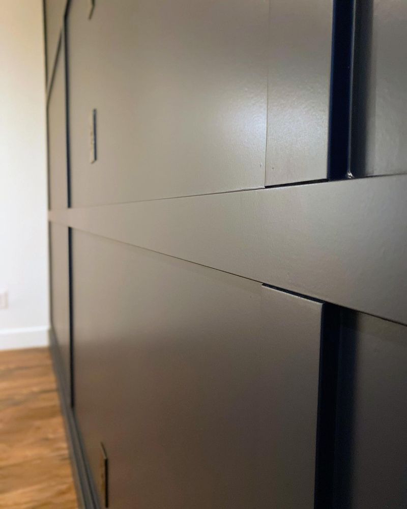 A close up of a black wall with a wooden floor