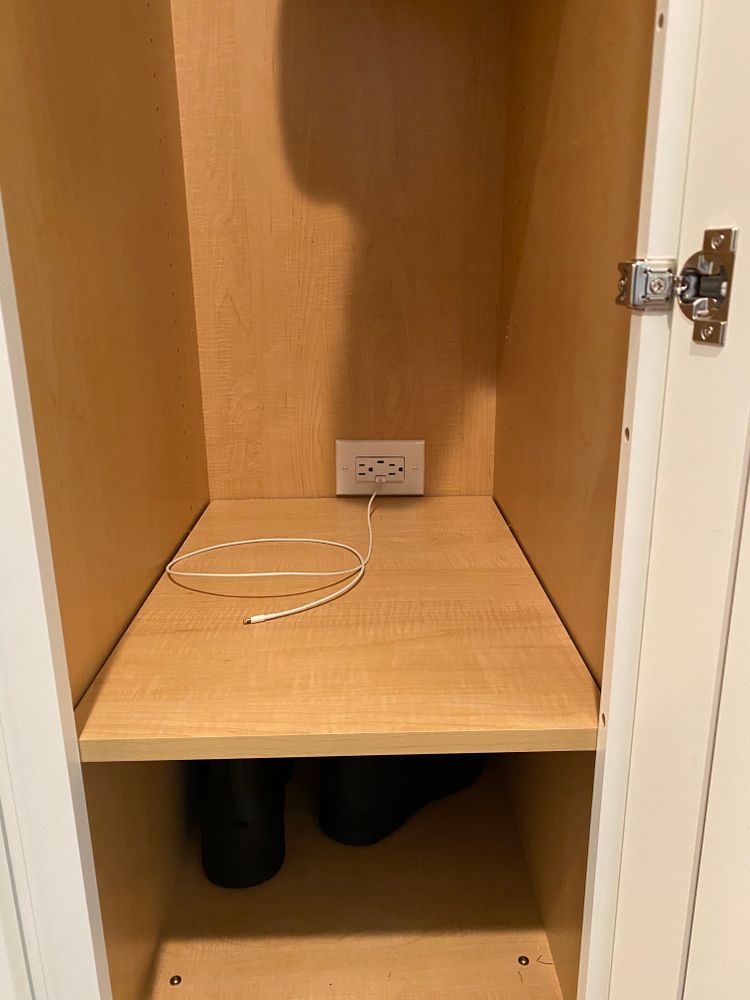 A shelf in a closet with a cord plugged into it.