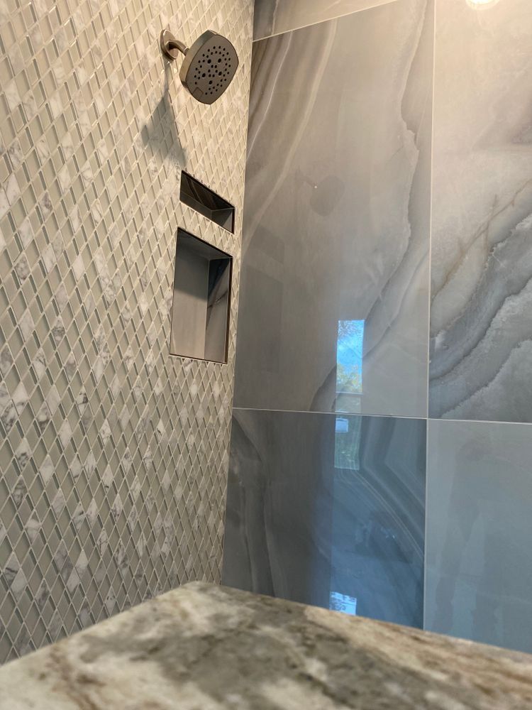 A shower with a shower head and a marble counter top.
