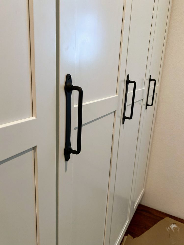 A row of white cabinets with black handles in a room.