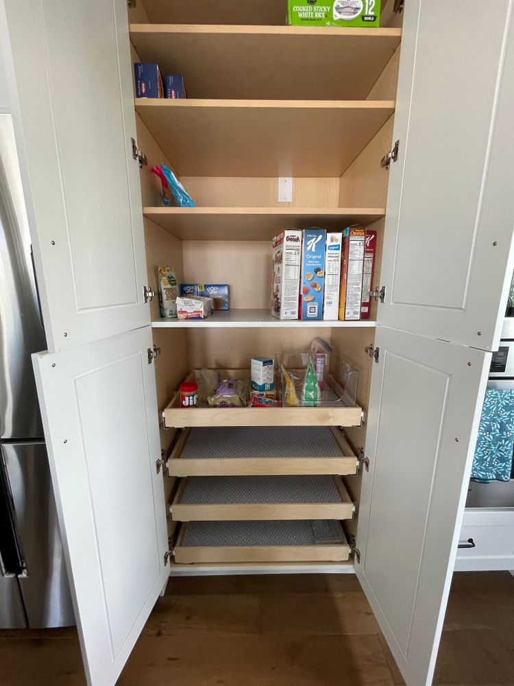A pantry with drawers and shelves filled with food in a kitchen.