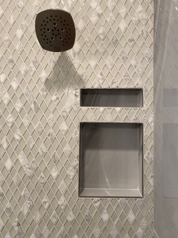 There is a shower head and a soap dish in the shower.