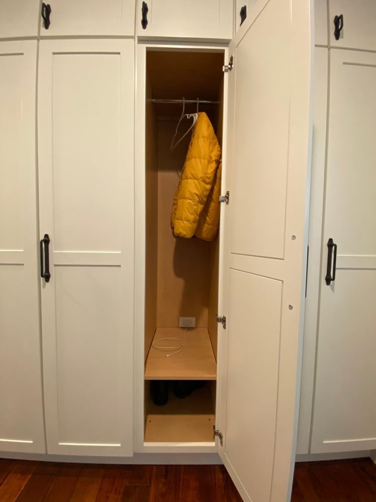 A yellow jacket is hanging in a closet with the door open