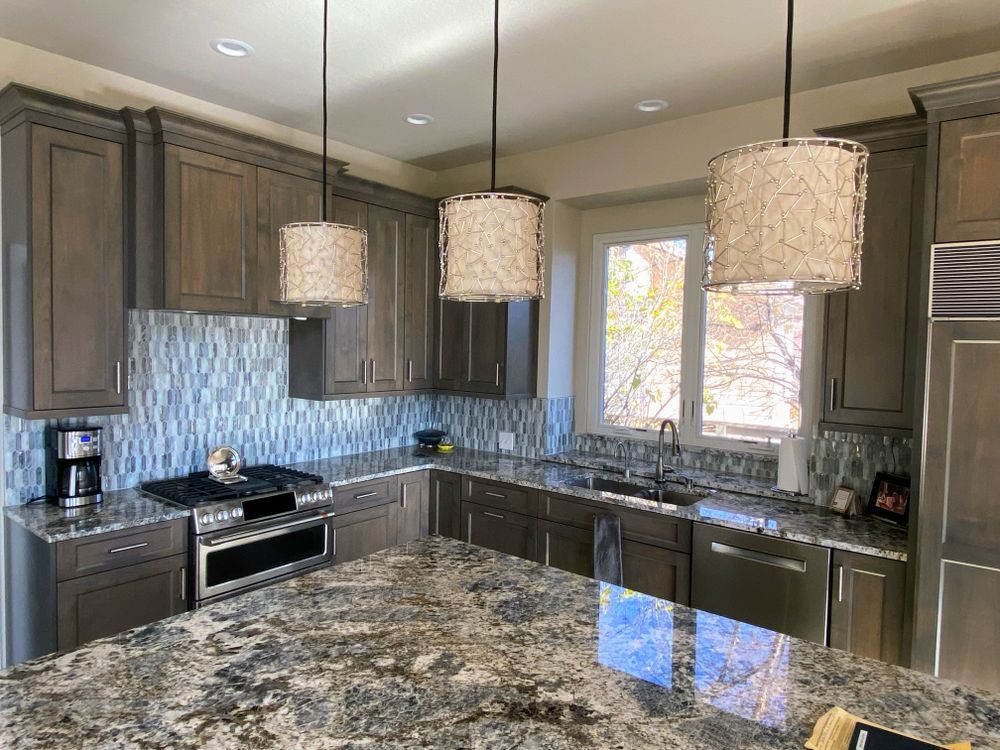 A kitchen with granite counter tops , stainless steel appliances , and gray cabinets.