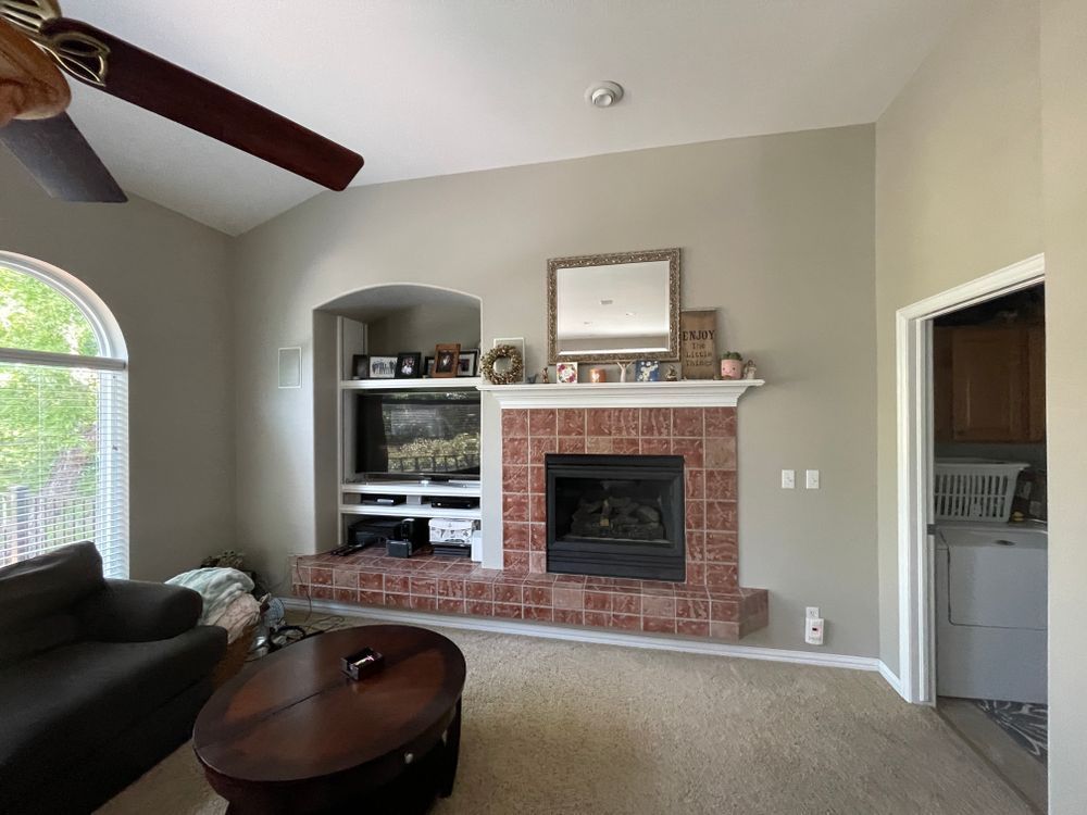 A living room with a fireplace and a ceiling fan