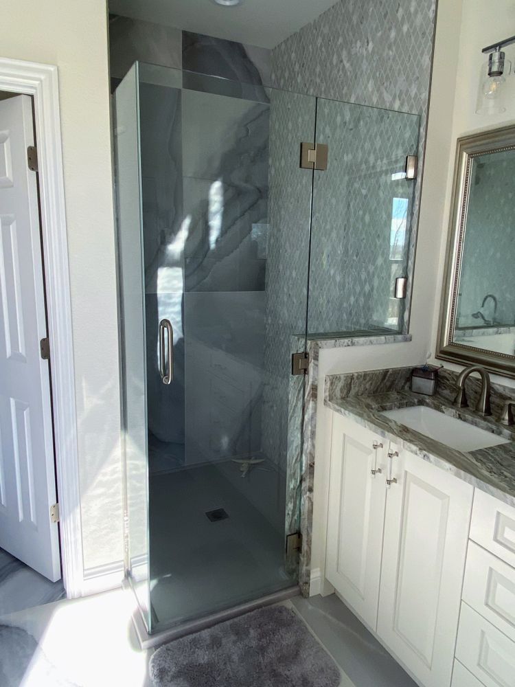A bathroom with a walk in shower and a sink