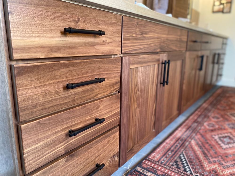 A kitchen with wooden cabinets and drawers and a rug on the floor.