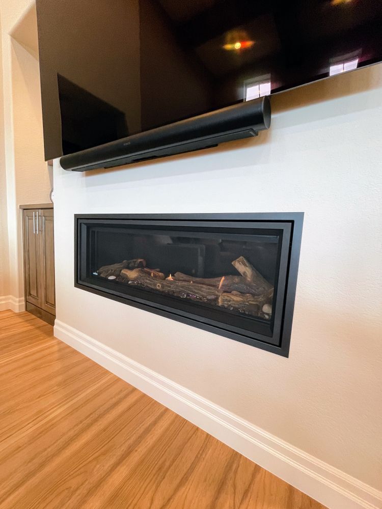 A fireplace with logs in it and a flat screen tv above it.