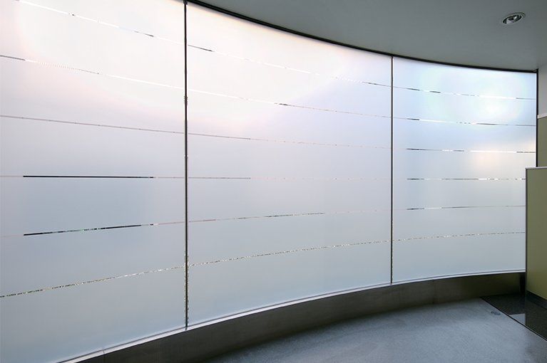 Curved frosted glass windows with horizontal lines, in a hallway.