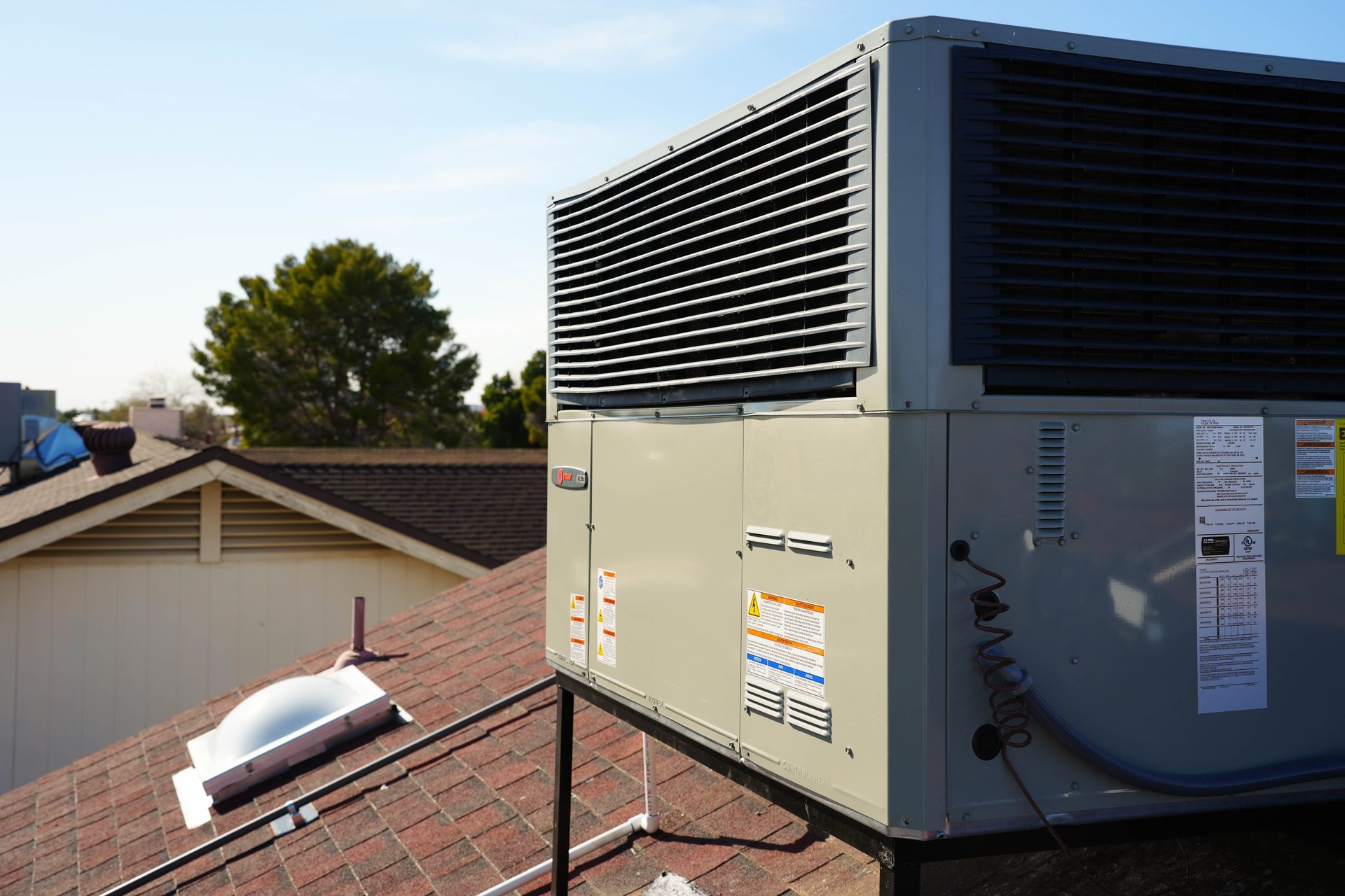Residential rooftop packaged HVAC unit installed on shingle roof in Phoenix, Arizona.
