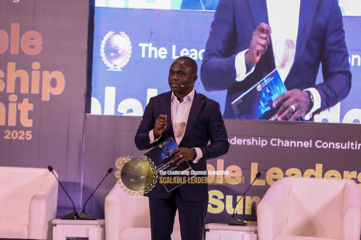 Man in suit speaking on stage at a leadership summit.