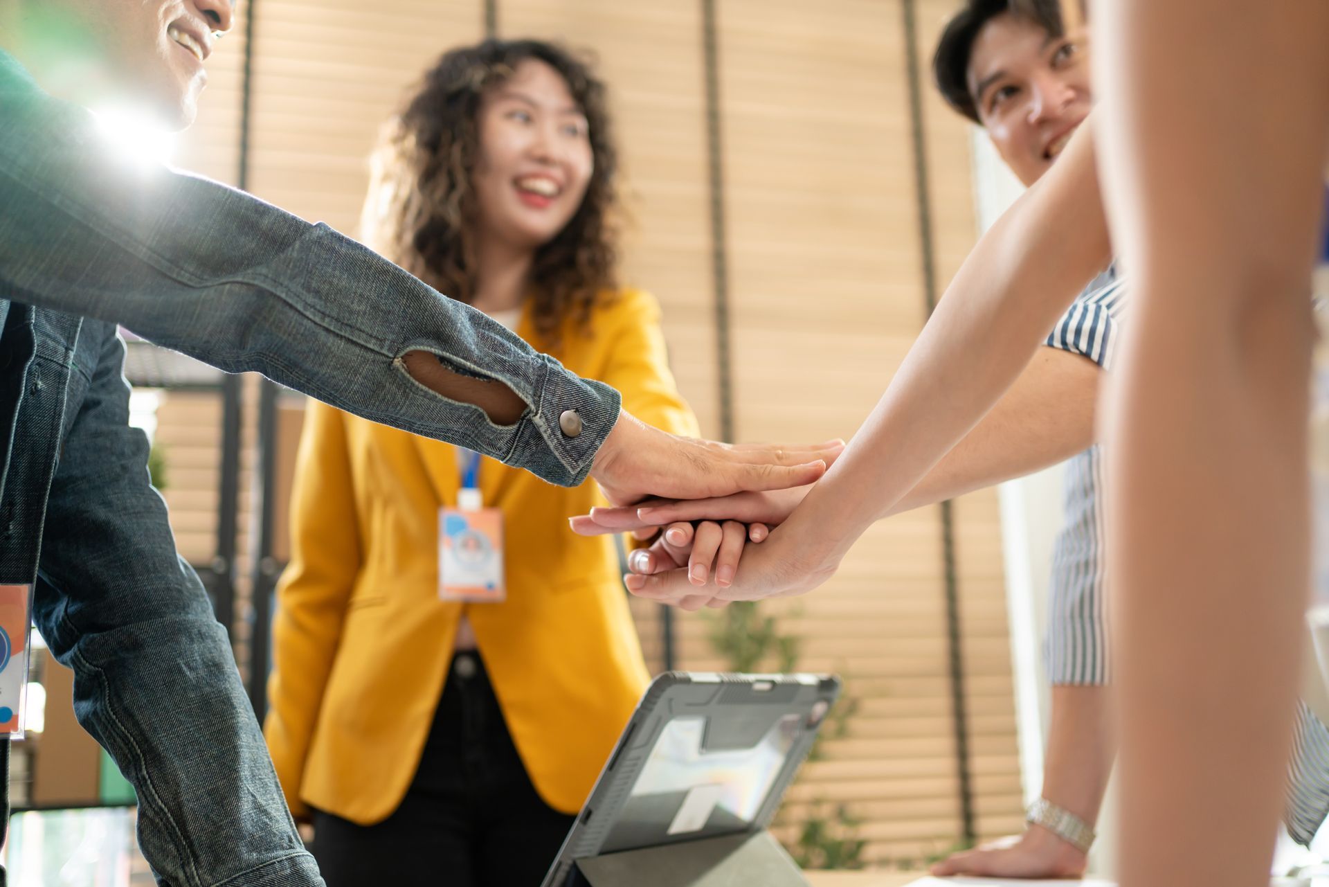 A group of people are putting their hands together in an office.