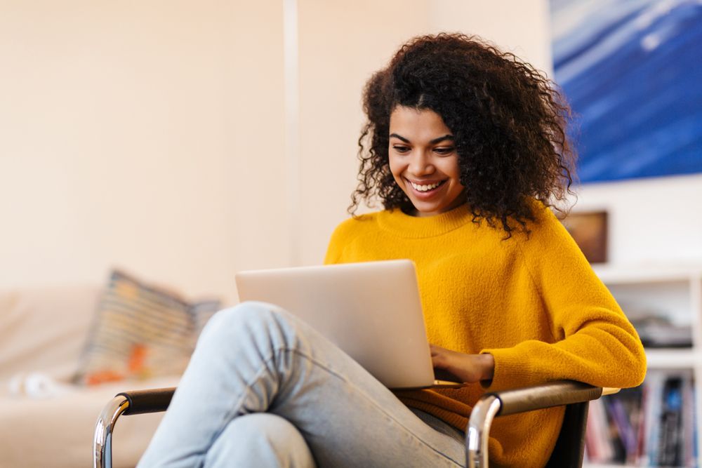 A woman is sitting in a chair using a laptop computer.