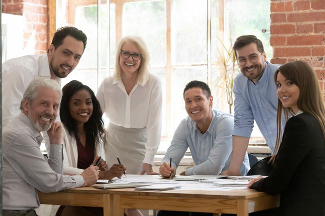 A group of people are sitting around a table in an office.