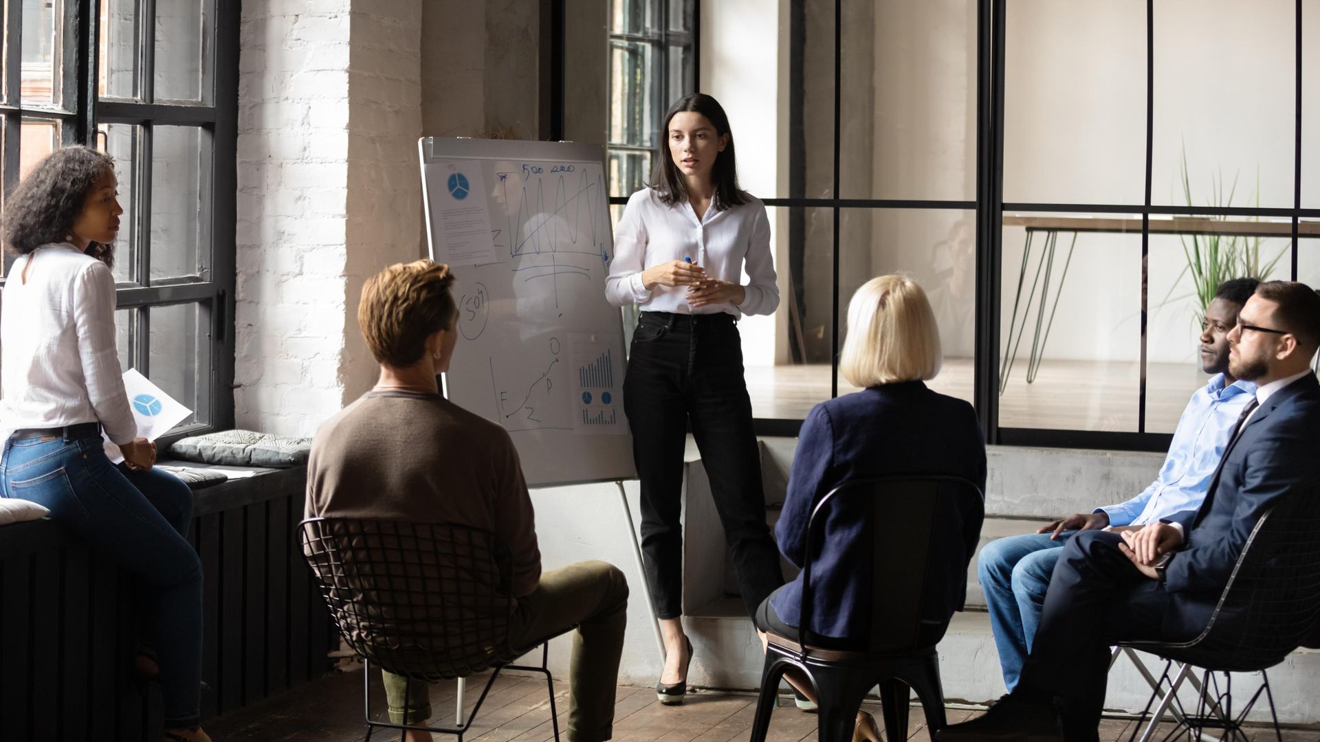 A woman is giving a presentation to a group of people sitting in chairs.