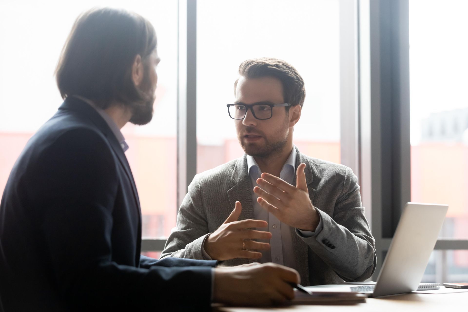 Two men are sitting at a table talking to each other.