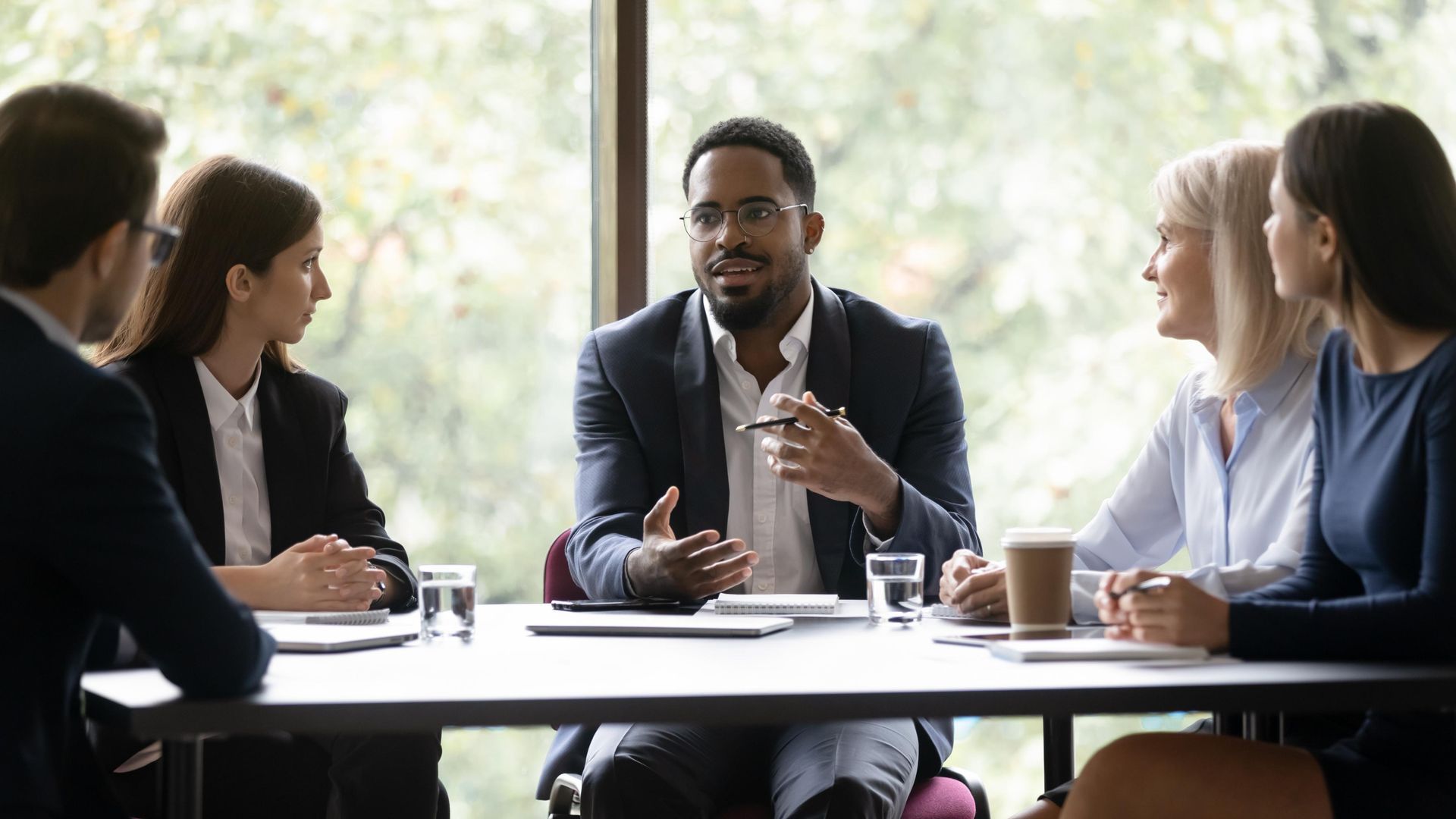 A group of people are sitting around a table having a meeting.