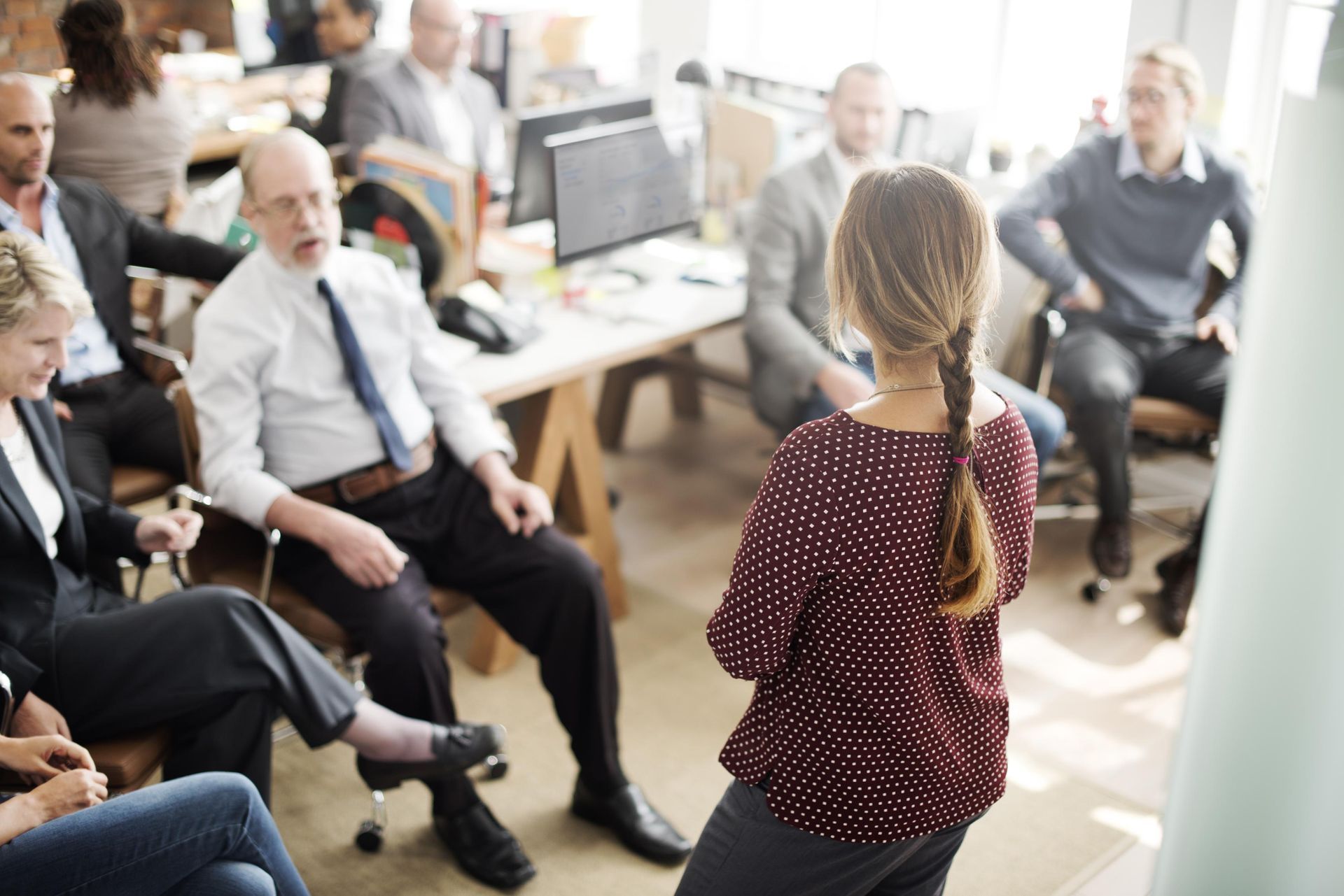 A woman is giving a presentation to a group of people in an office.