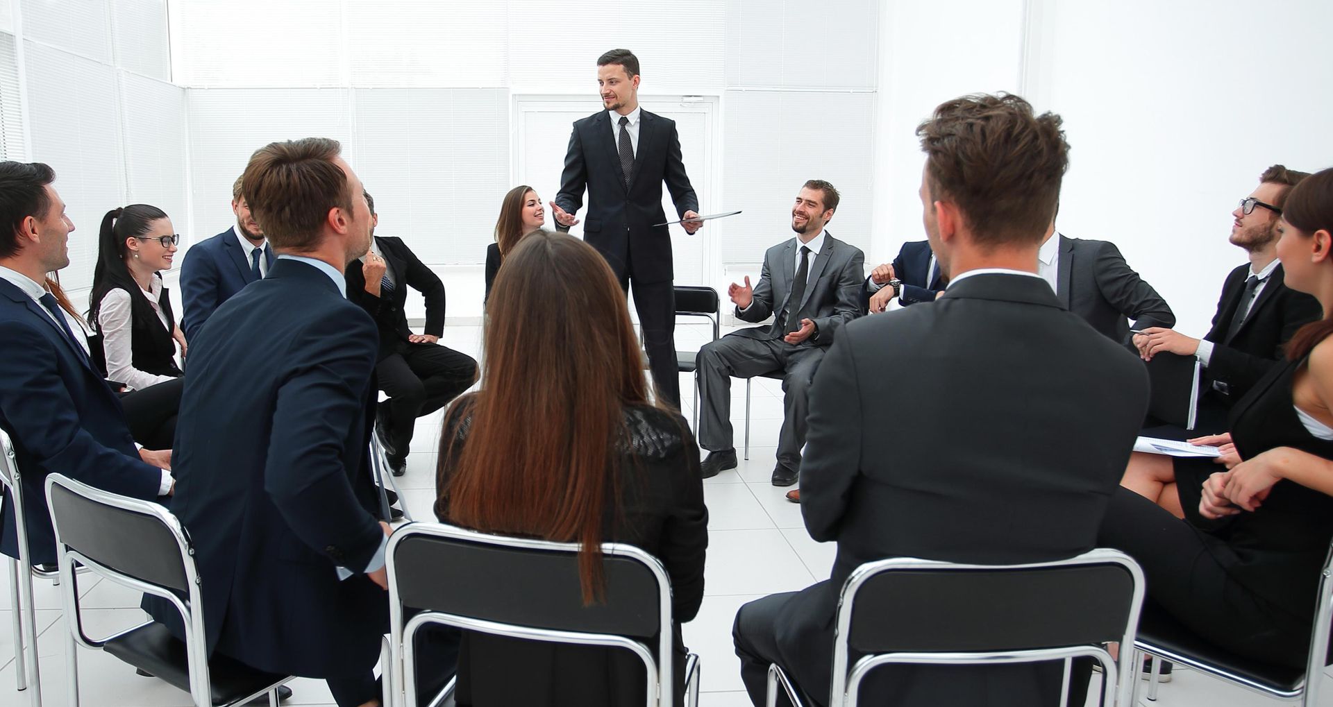 A man is giving a presentation to a group of business people sitting in a circle.