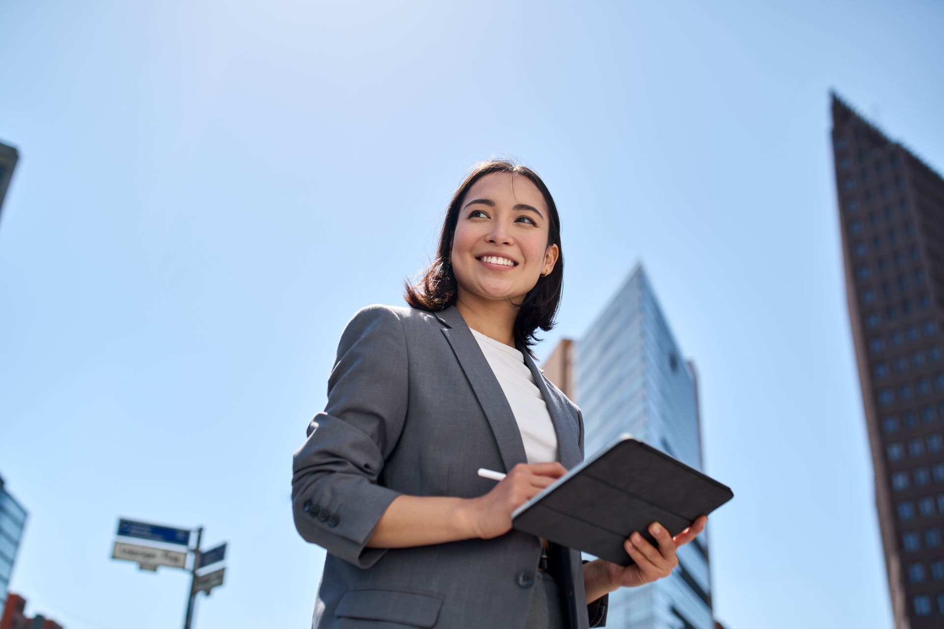 A woman in a suit is holding a clipboard in front of a city skyline.