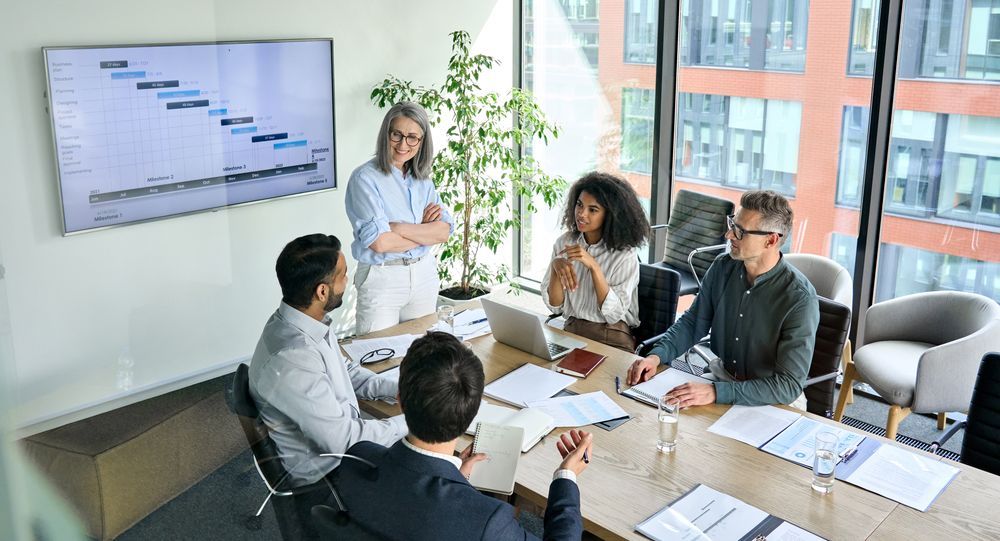 A group of people are sitting around a table in a conference room having a meeting.