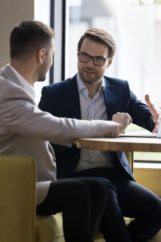 Two men are sitting at a table having a conversation.