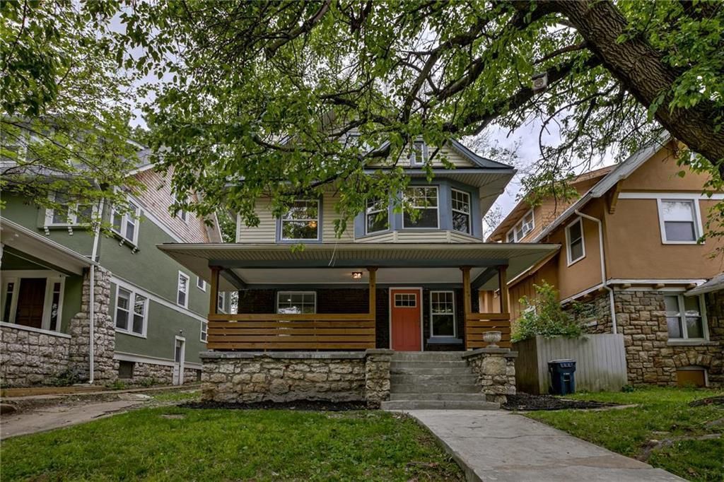 a house with a red door and a large tree in front of it .