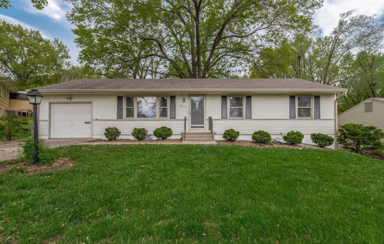 a white house with a large lawn in front of it .