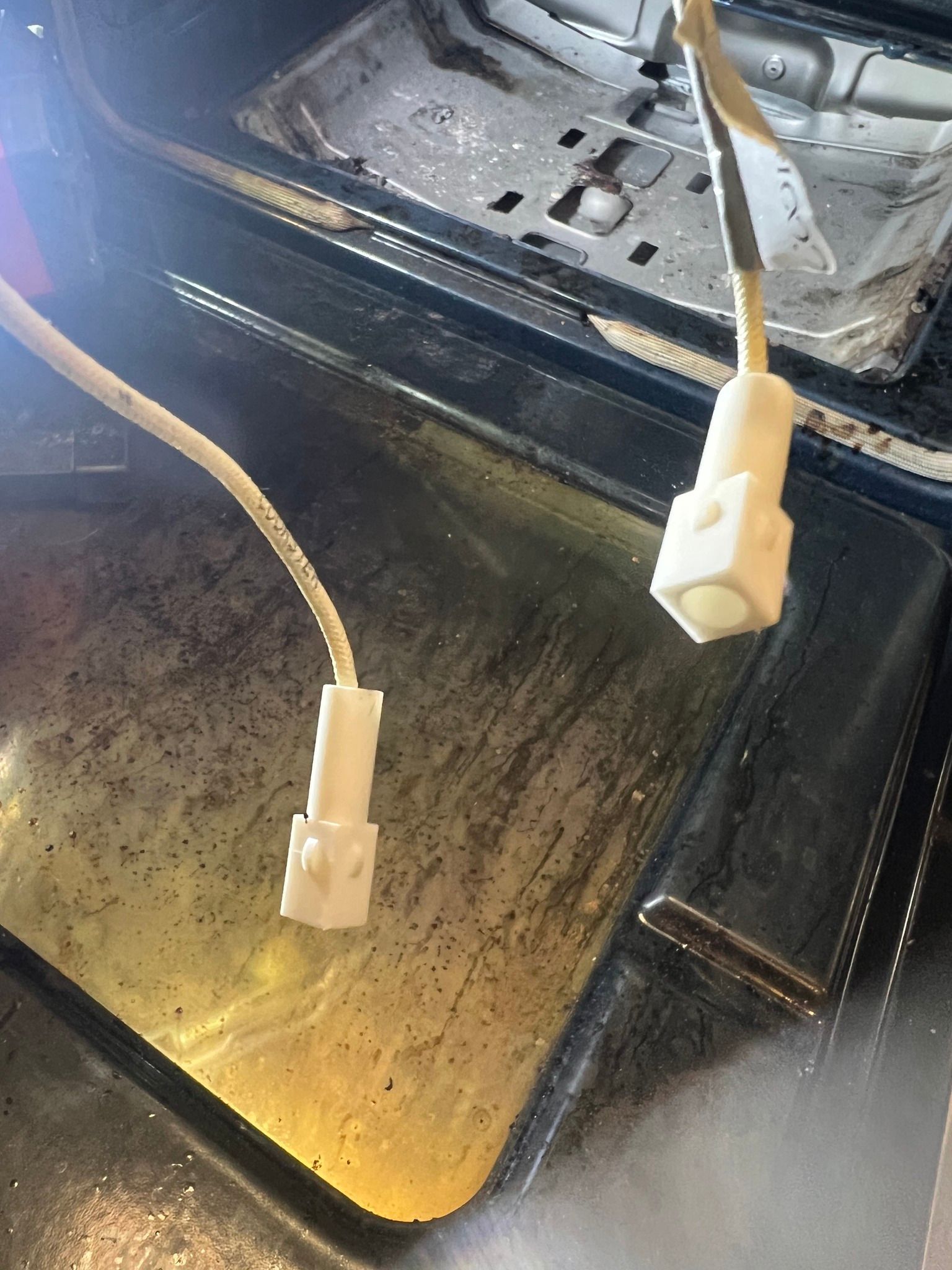 Two wires are connected to a dirty oven door.