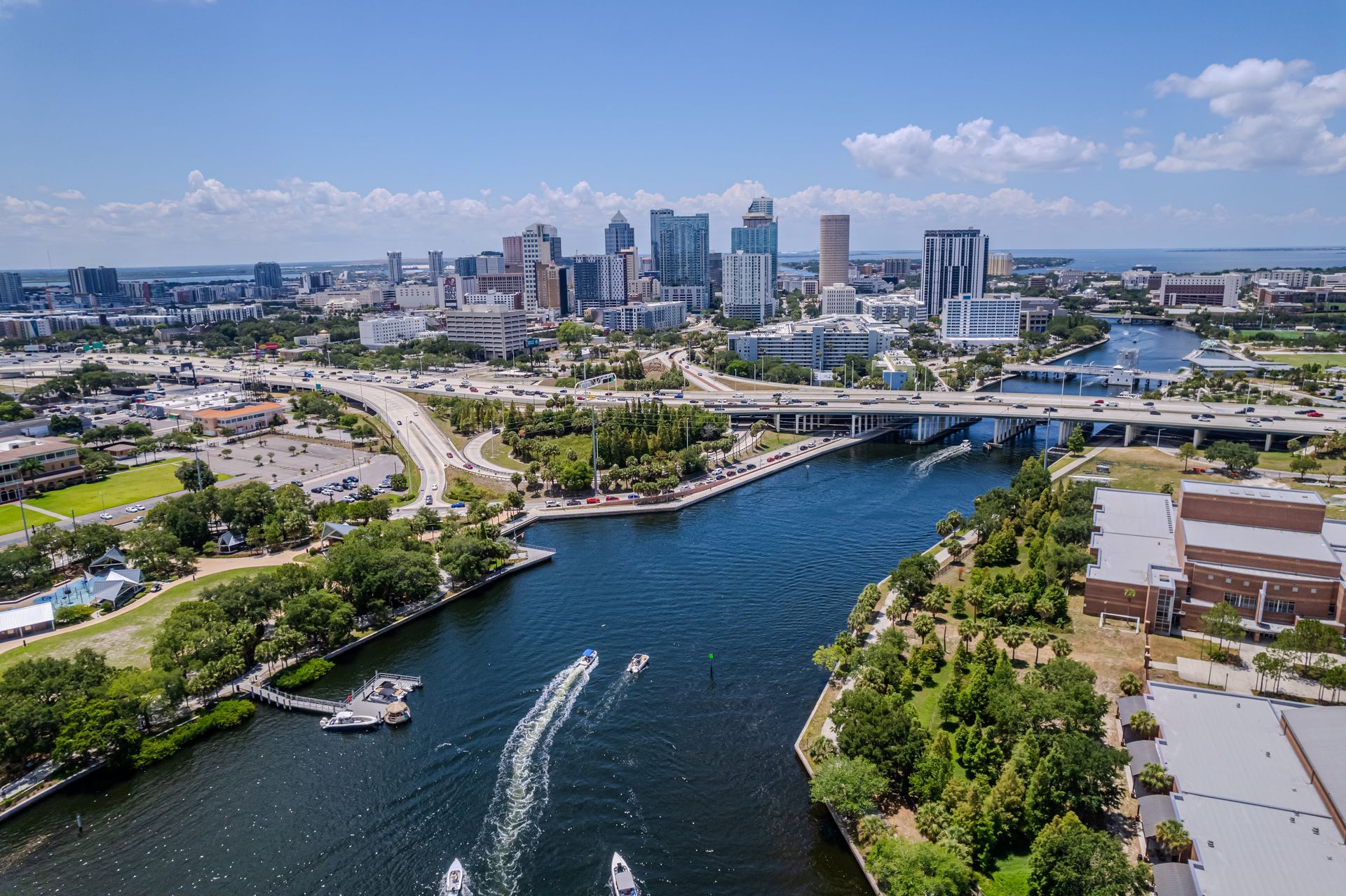 Aerial view of Tampa, Florida, with a river in the foreground and the city skyline in the background under a clear blue sky.