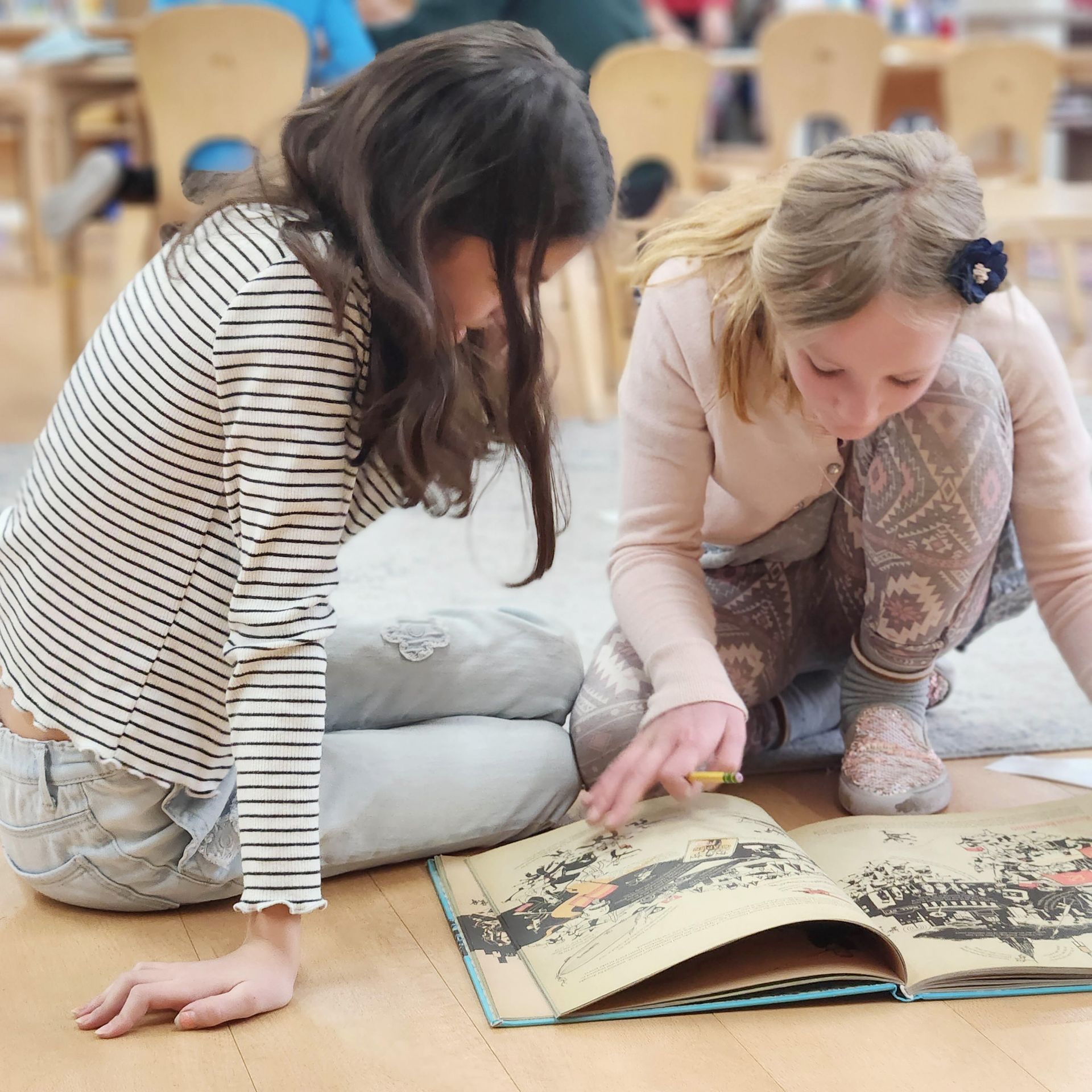 Two Montessori children reading a book in the classroom