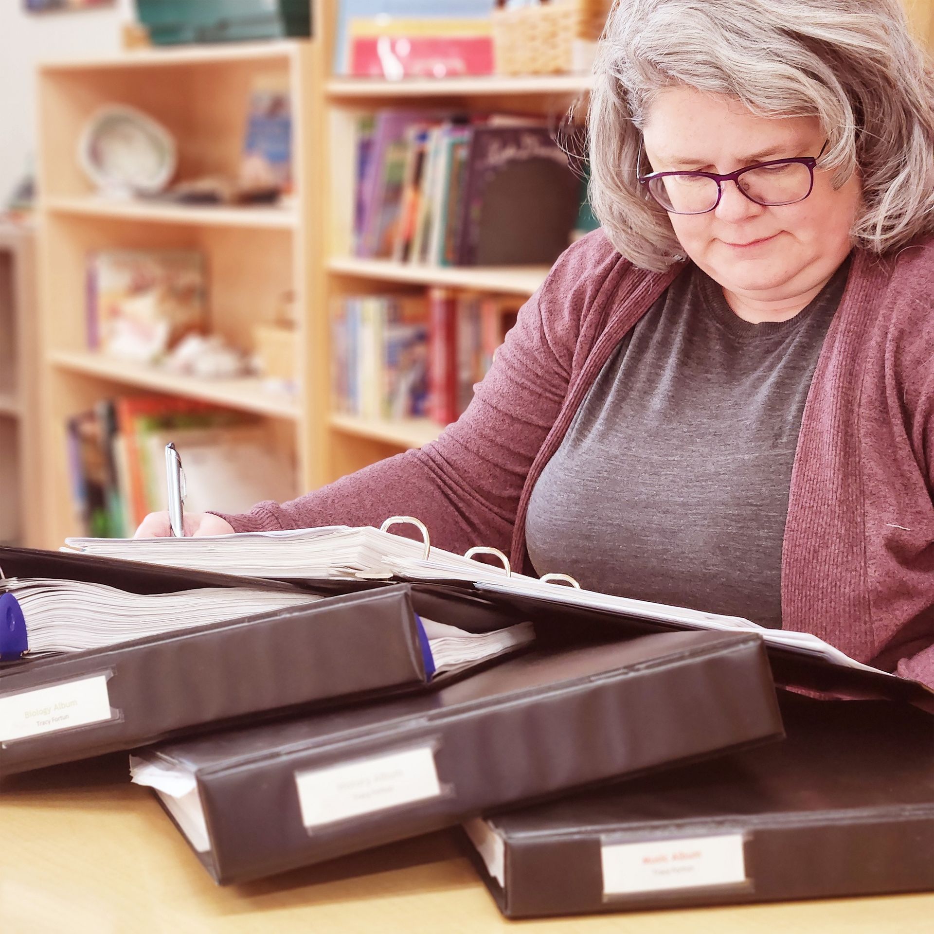 A montessori guide is sitting at a desk with binders on it