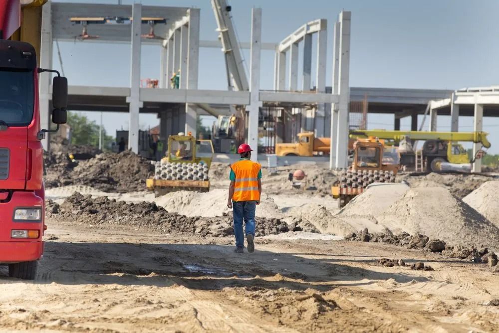 Construction Site With a Worker in Orange Vest and Red Hard Hat — Coastal Surveying Group Pty Ltd In Baringa, QLD