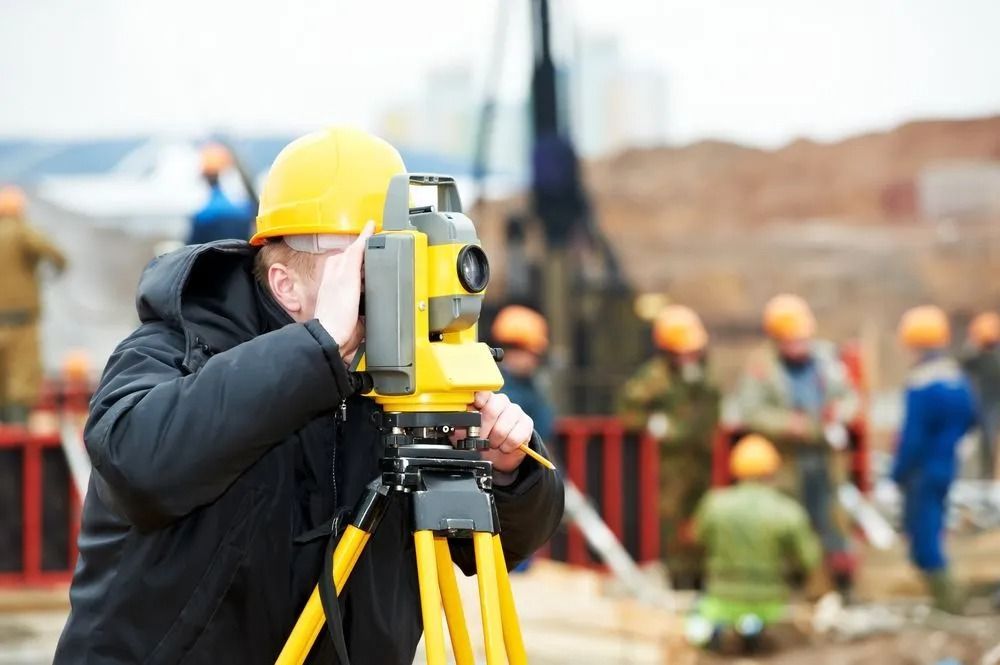 Surveyor in Yellow Hard Hat Using a Total Station at a Construction Site — Coastal Surveying Group Pty Ltd In Baringa, QLD