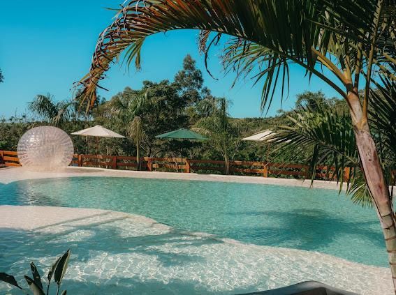 Vista aérea de um resort com piscina, vários edifícios e vegetação exuberante.