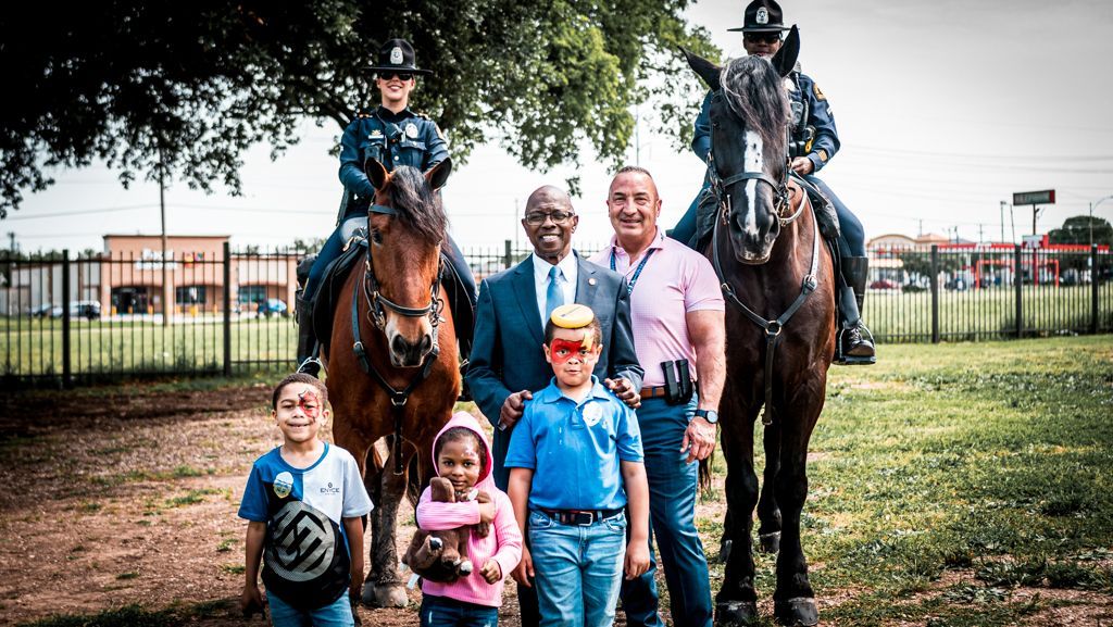 A group of people standing next to horses and police officers.