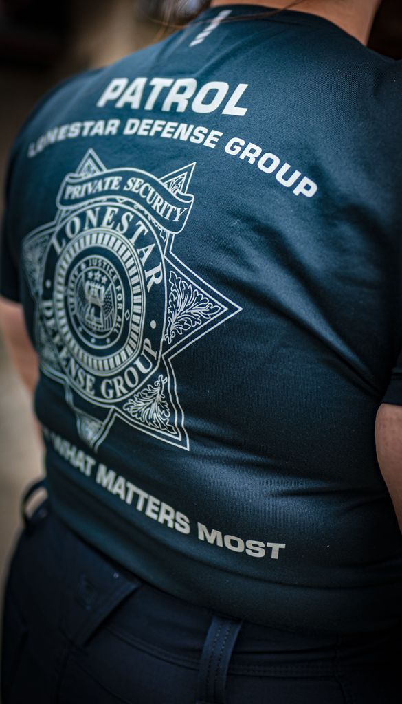 The back of a person wearing a patrol defense group shirt.