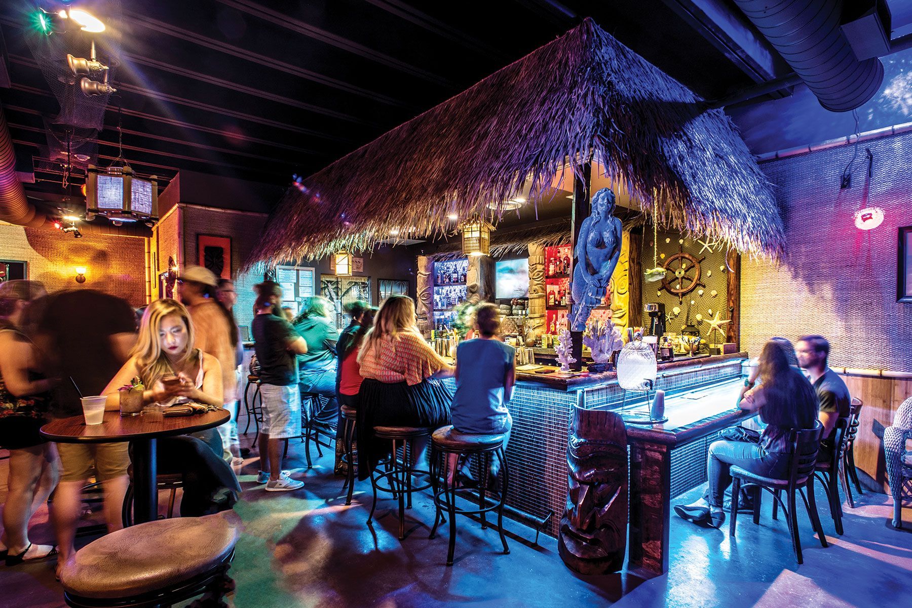 A group of people are sitting at tables in a bar.