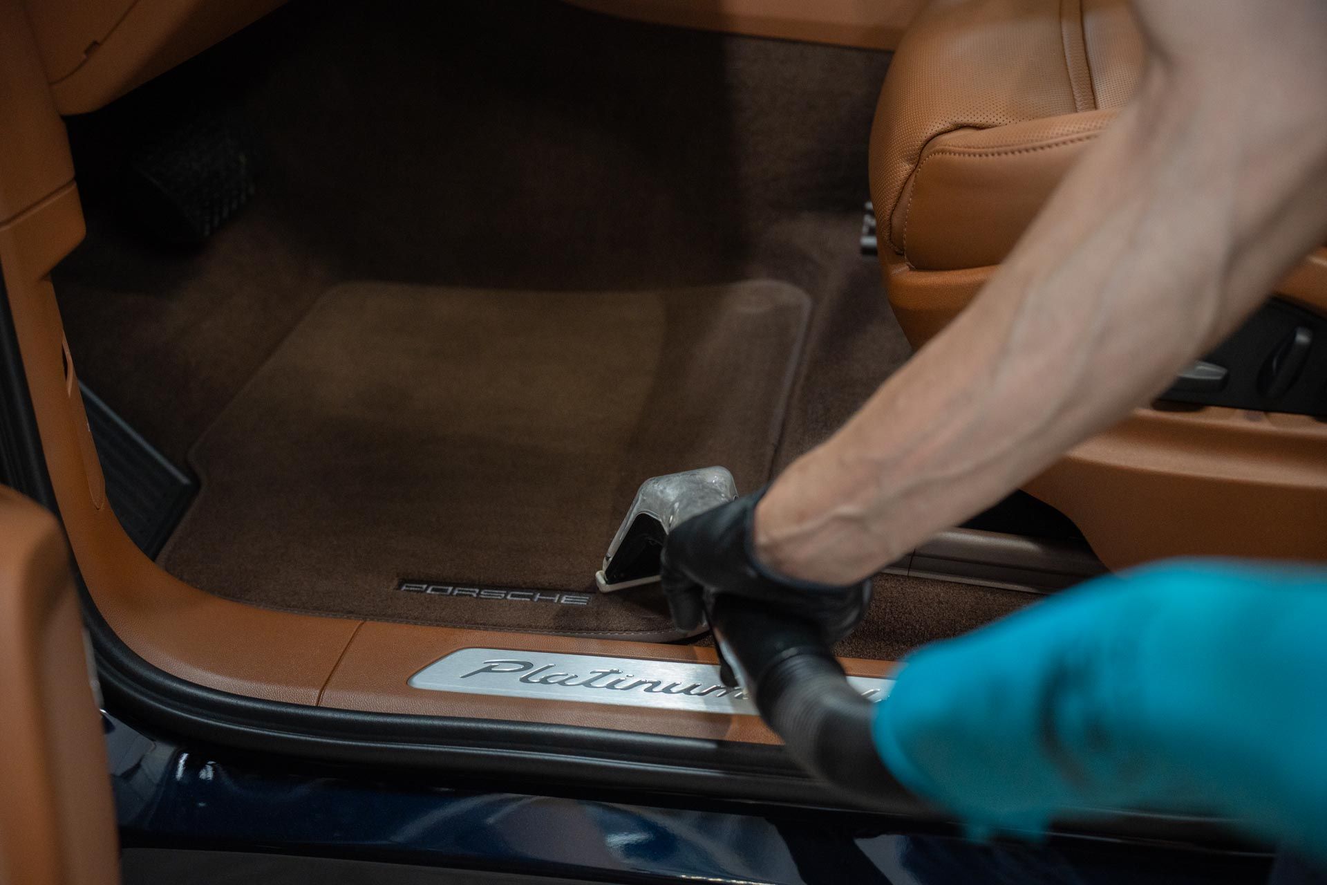 A person is using a vacuum cleaner to clean the interior of a car.