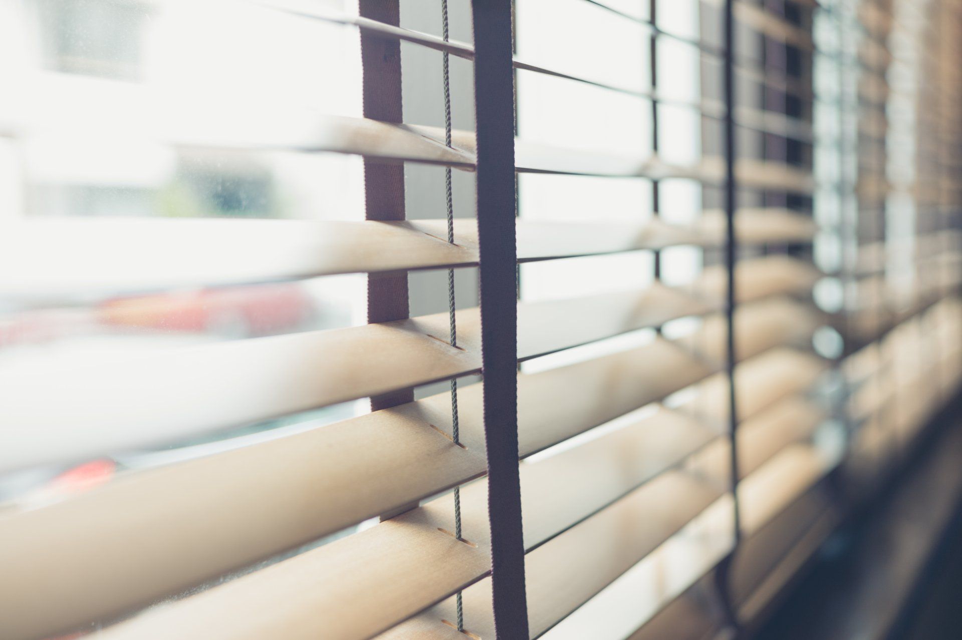 Close up of timber venetian blinds, open with blurred view out window.