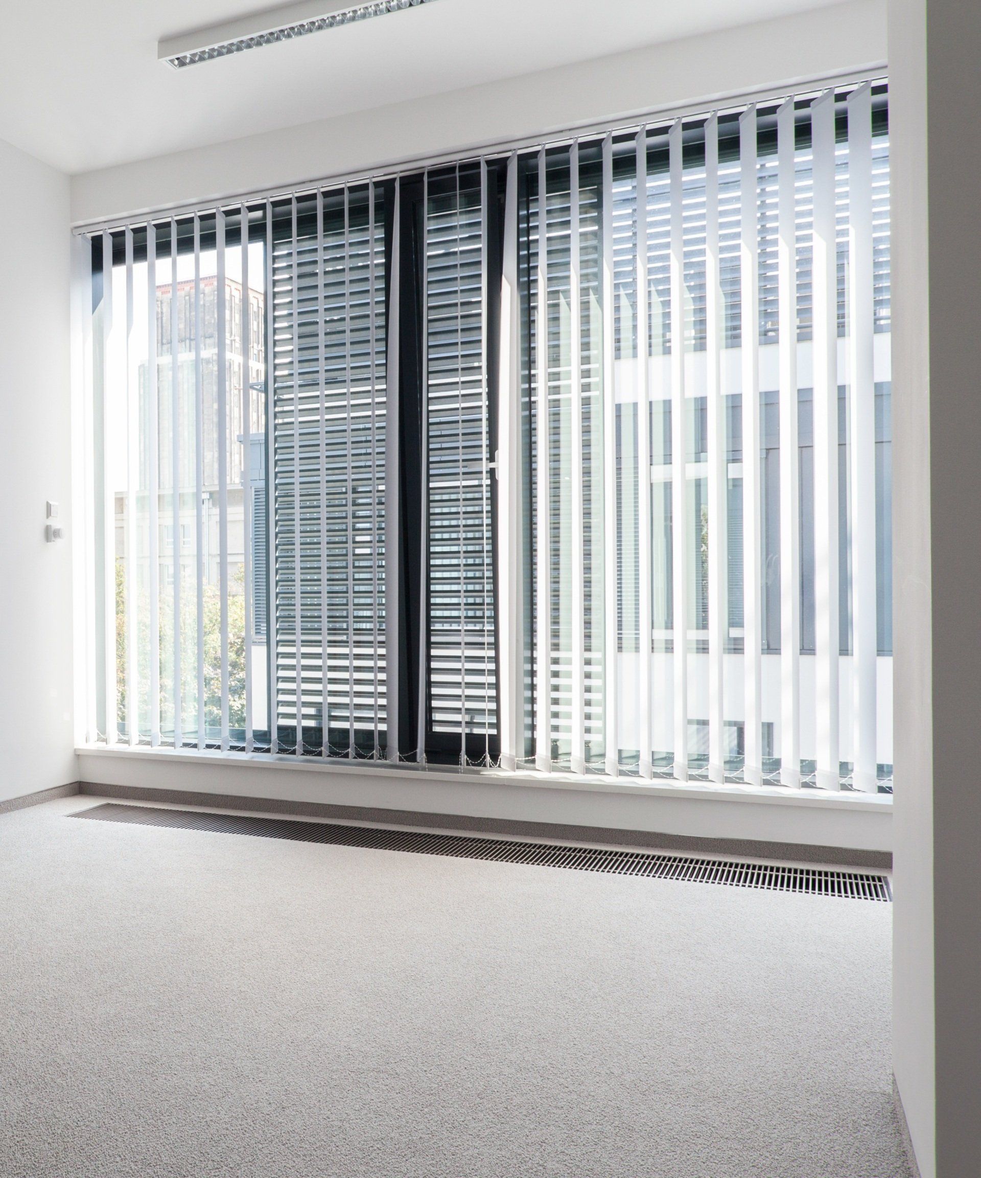 Open vertical blinds in empty, carpeted, high rise office.